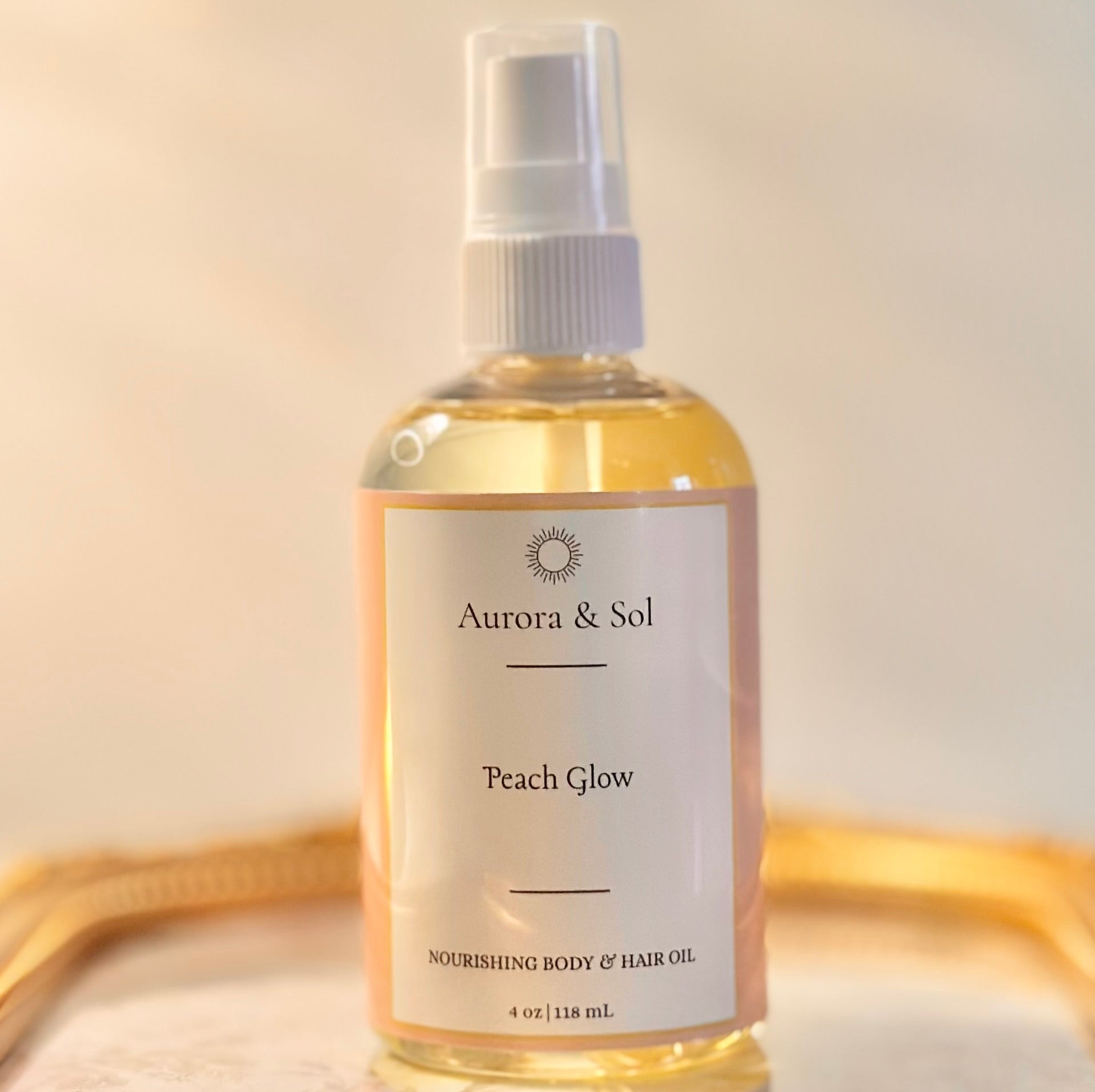 Aurora & Sol Peach Glow body and hair oil bottle on a gold tray with a beige background