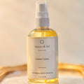 Bottle of Aurora & Sol Lemon Crème body and hair oil on a reflective surface with a neutral background