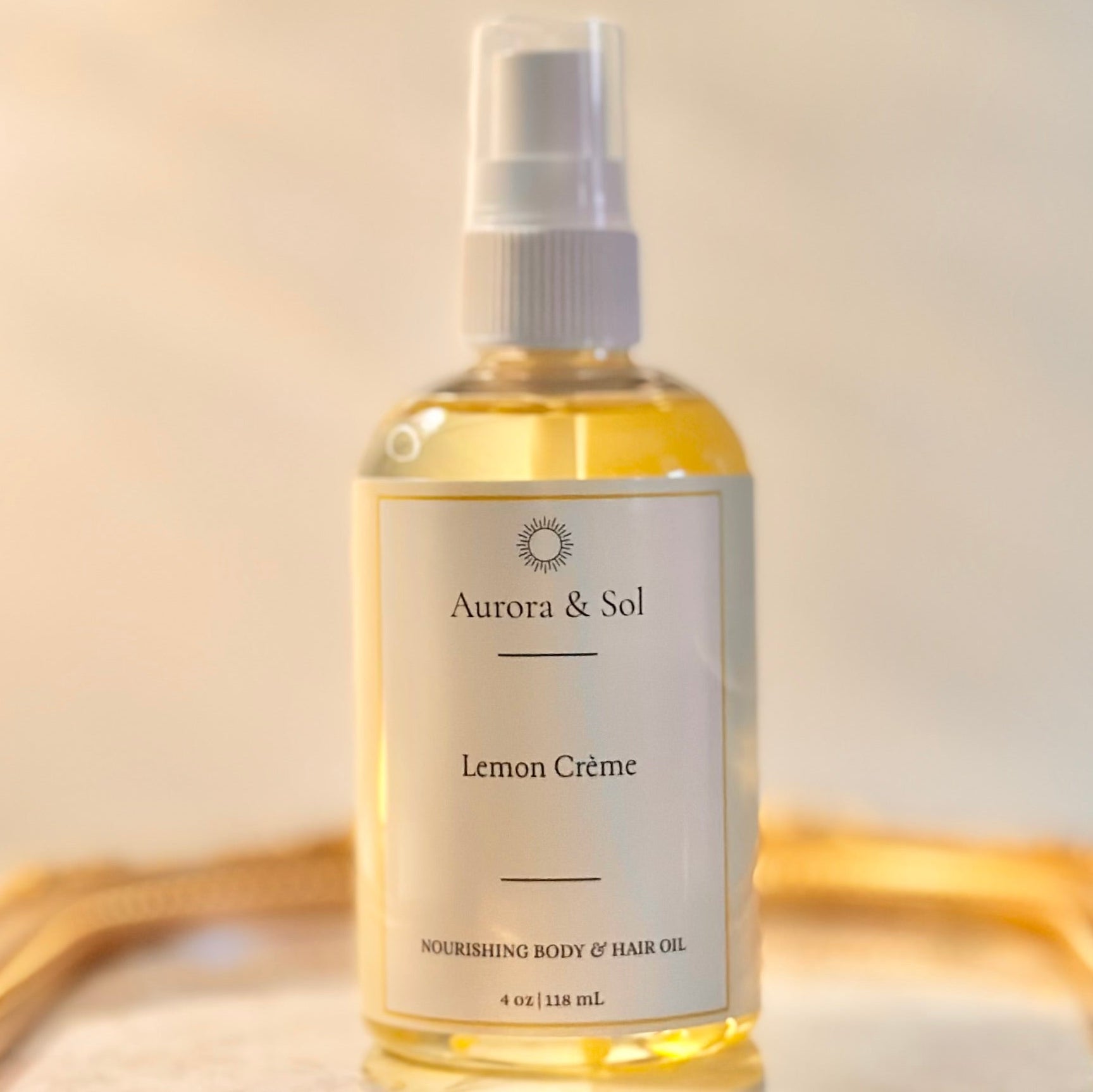 Bottle of Aurora & Sol Lemon Crème body and hair oil on a reflective surface with a neutral background
