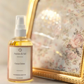 A bottle of Aurora & Sol Cocco Creme body oil next to a decorative mirror with floral design.