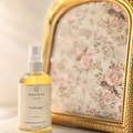A bottle of Aurora & Sol Vanilla hug! product next to a decorative gold frame with floral design.