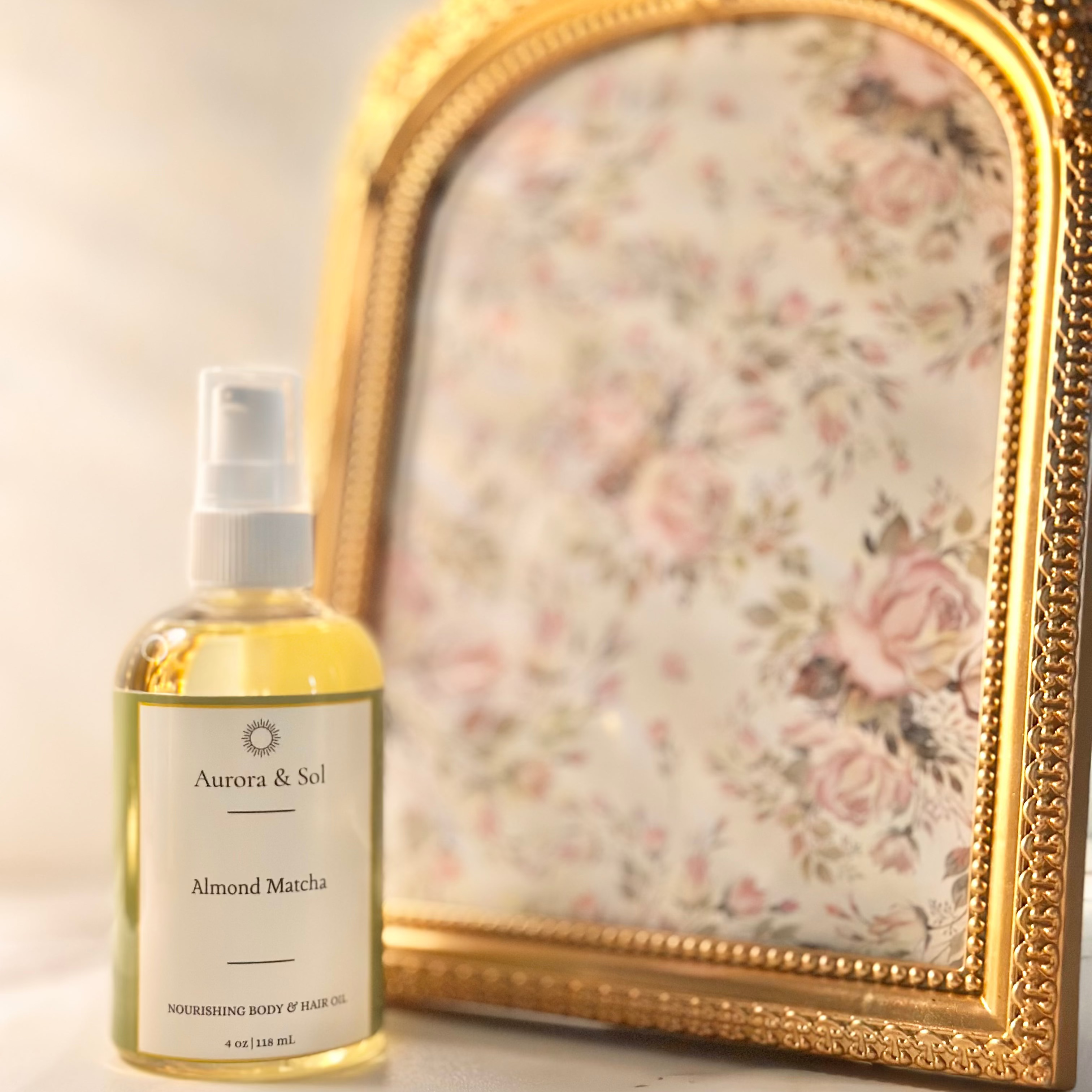A bottle of Aurora & Sol Almond Matcha product next to a decorative mirror with floral design.