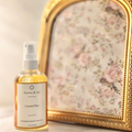 A bottle of 'Aurora & Sol Caramel Kim' product on a marble surface with a decorative gold frame in the background.