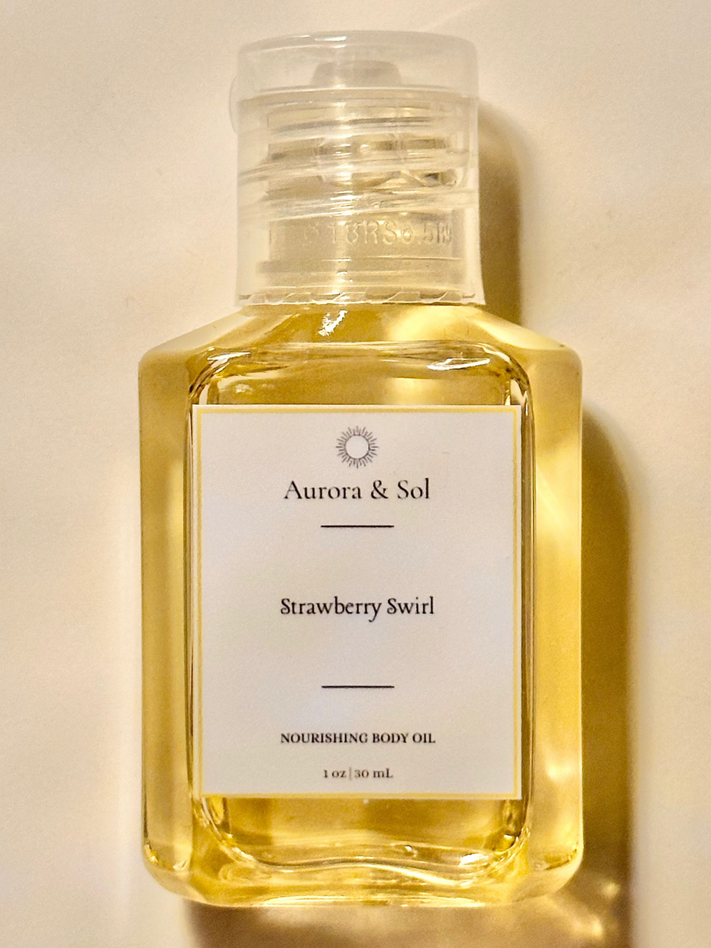 Aurora & Sol Strawberry Swirl body oil bottle on a beige background