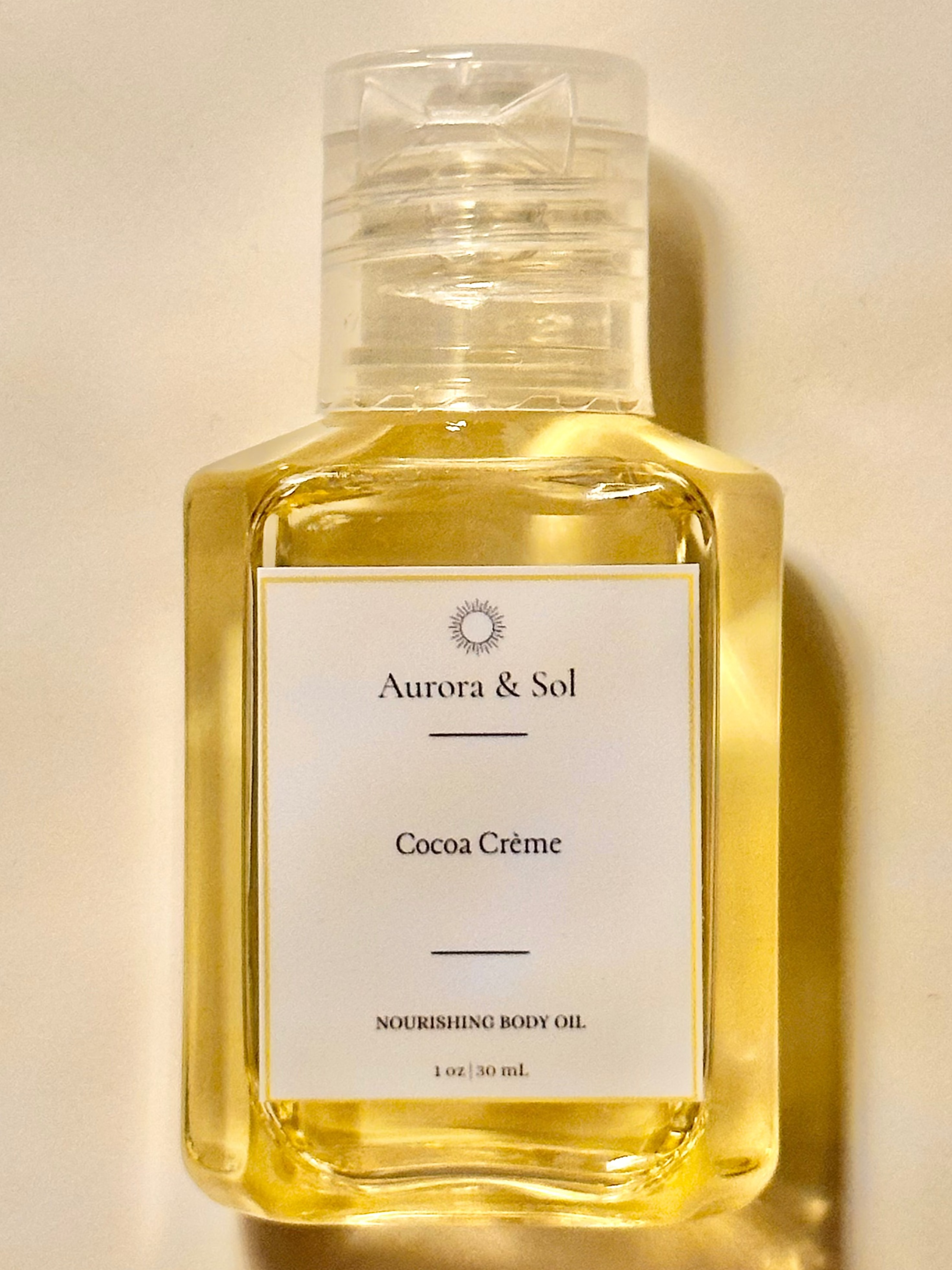Aurora & Sol Cocoa Crème body oil bottle on a beige background